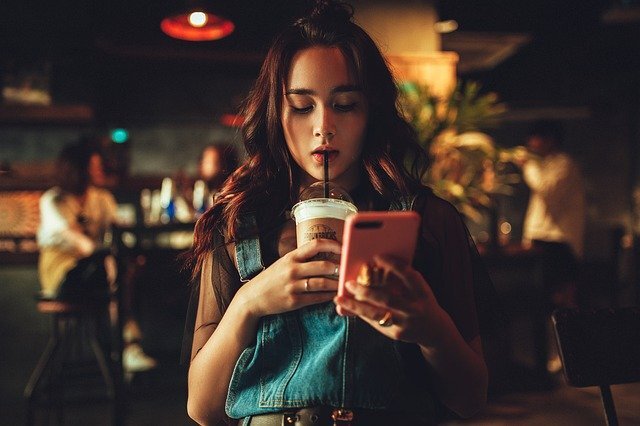 millennial sipping on drink while on her phone