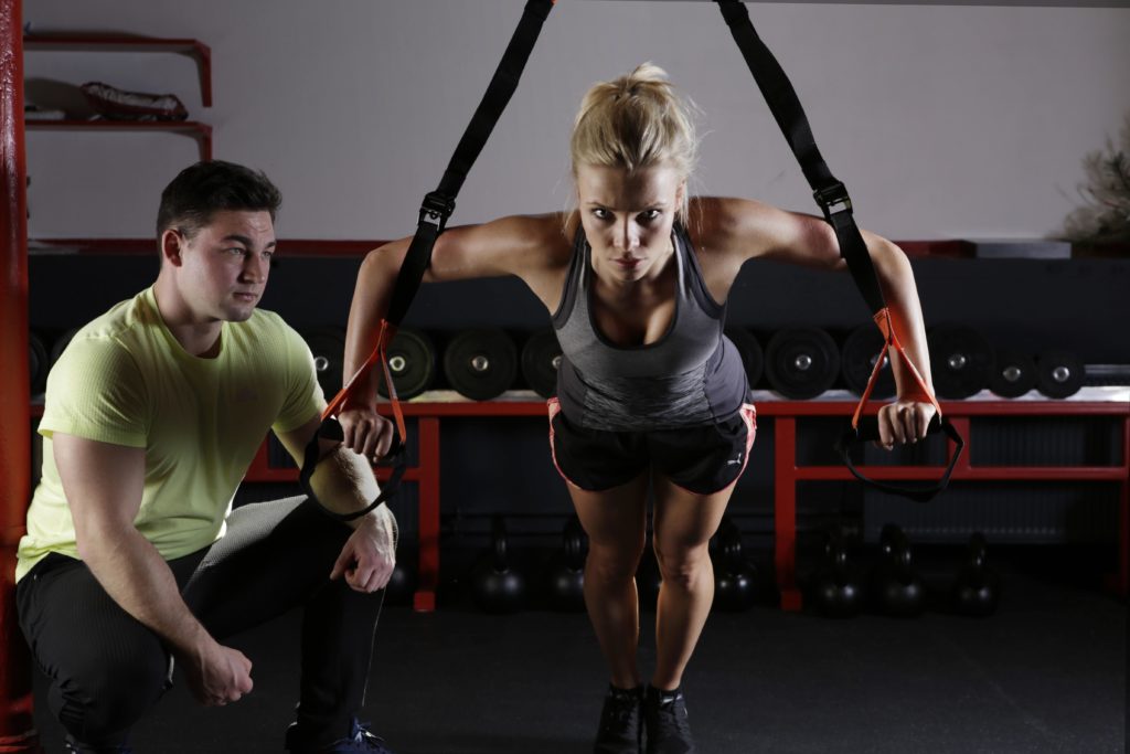 woman exercising under supervision of a male personal trainer